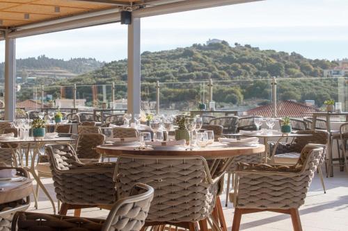 a restaurant with tables and chairs with a mountain in the background at Almyrida Resort in Almirida