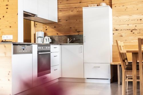 a kitchen with white appliances and a wooden wall at Schrannenhof in Schoppernau