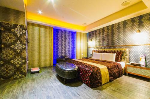 a hotel room with a bed and a ottoman in it at Wsb Motel-Rende in Tainan