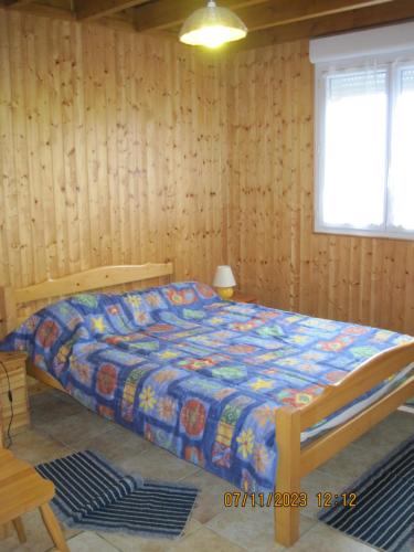 een slaapkamer met een bed in een kamer met houten wanden bij 77 Rue de la Bresse in Nance
