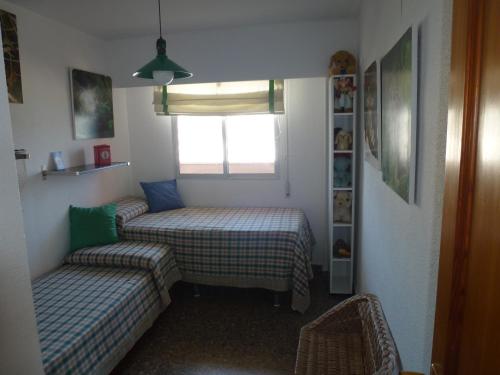 una piccola camera con due letti e una finestra di Espectacular terraza y vistas en 1a línea de playa a Cullera
