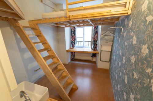 a loft bed in a tiny room with a sink at Sishaus Hostel in Graz