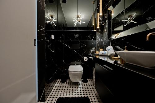 a black bathroom with a white toilet and a sink at Apartamenty Belni Hel Edyta i Maciej Wolak in Hel