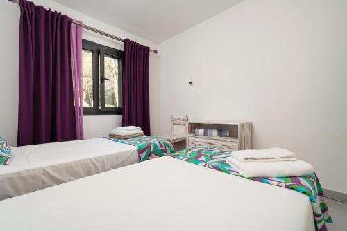 twee bedden in een kamer met paarse gordijnen bij Ca na Carmen -Crestatx- in Crestatx