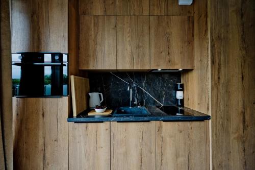 a kitchen with a sink and wooden cabinets at Apartamenty Belni Hel Edyta i Maciej Wolak in Hel