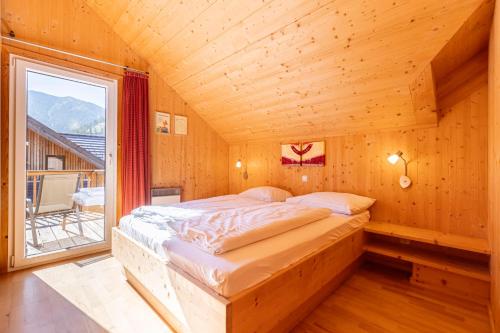 a bed in a wooden room with a large window at Almdorf Hohentauern by ALPS RESORTS in Hohentauern
