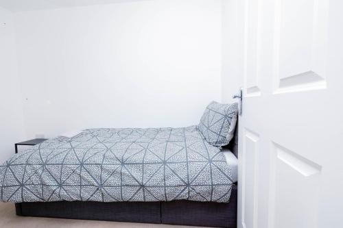 uma cama num quarto com uma parede branca em Perfect Stay Rugby em Rugby