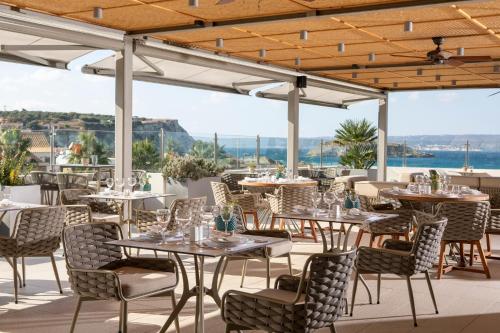 a restaurant with tables and chairs on a patio at Almyrida Resort in Almirida