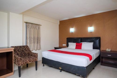 Habitación de hotel con cama y silla en RedDoorz Plus At Grand Populer Hotel en Makassar
