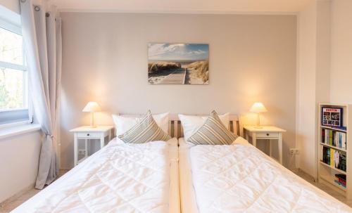 a bedroom with a white bed with two tables and two lamps at Ferienwohnung Zeitlos in Kappeln