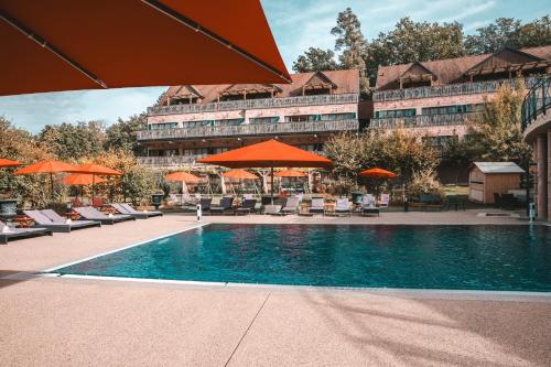 a hotel with a swimming pool with chairs and umbrellas at Les Violettes Hotel & Spa in Jungholtz