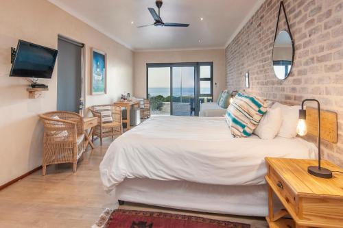 a bedroom with a bed and a table and a tv at Spookdraai B&B in Agulhas