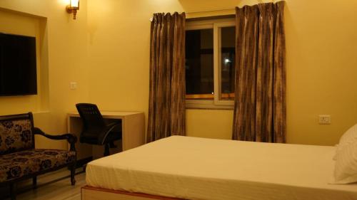 ein Schlafzimmer mit einem Bett, einem Stuhl und einem Fenster in der Unterkunft Oak Villa in Ranchi