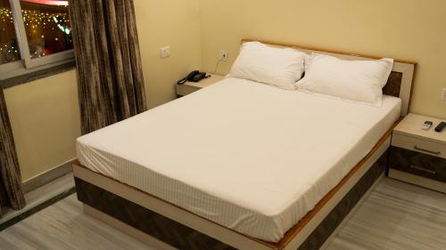 Bett mit weißer Bettwäsche und Kissen in einem Zimmer in der Unterkunft Oak Villa in Ranchi
