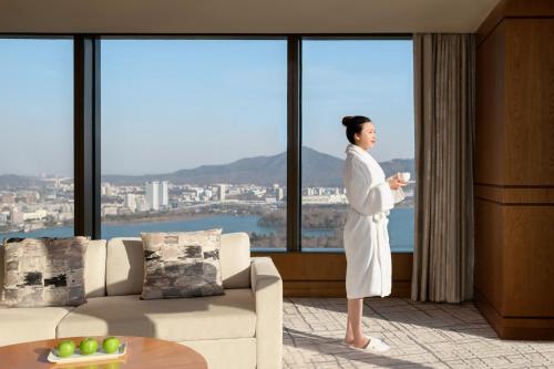 a woman standing in a room looking out the window at Shangri-La Nanjing in Nanjing