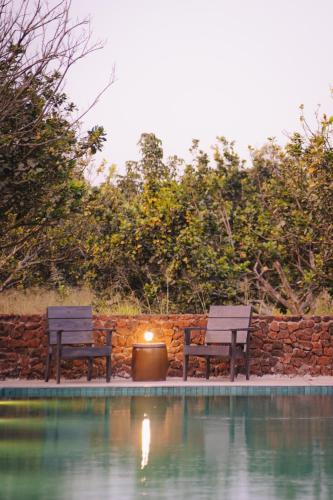 two benches sitting next to a wall next to a pool at Suối Camp in Ba Ria
