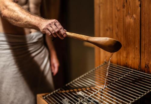 a person holding a wooden spoon cooking on a grill at Hotel Elisabeth in Schoppernau
