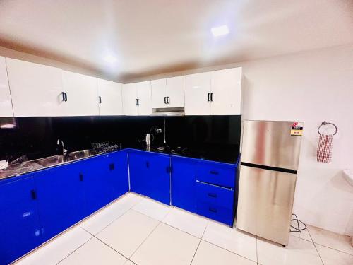 cocina con armarios azules y nevera de acero inoxidable en HomeStay Private Home, en Suva