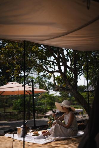 a woman sitting on a blanket under a tent at Suối Camp in Ba Ria