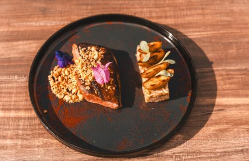 a black plate with two slices of cake and nuts at Les Violettes Hotel & Spa in Jungholtz
