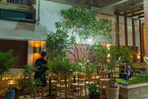 um homem de pé numa sala com árvores e cadeiras em Su's Villa Hà Giang - Biệt thự nguyên căn tại trung tâm thành phố Hà Giang em Ha Giang