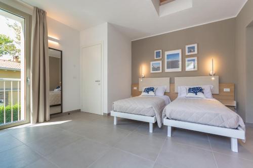 a bedroom with two beds and a large window at Isola di Albarella in Isola Albarella