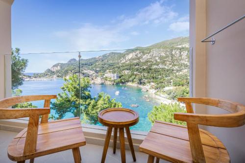 a room with two chairs and a large window at Akrotiri Beach Resort Hotel - Adult Friendly in Paleokastritsa