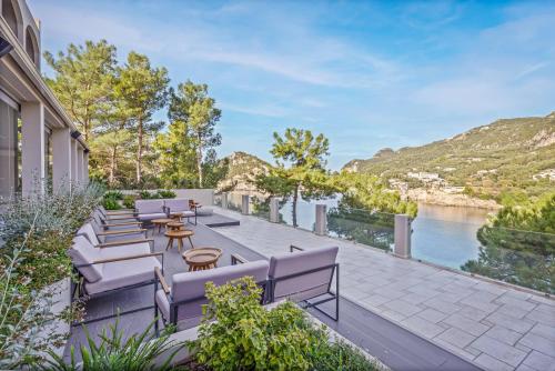 a patio with chairs and tables and a view of the water at Akrotiri Beach Resort Hotel - Adult Friendly in Paleokastritsa