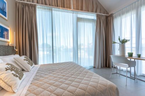 a bedroom with a bed and a desk and windows at Isola di Albarella in Isola Albarella