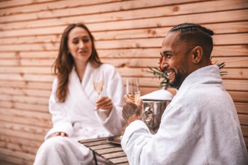 a man and a woman holding glasses of wine at Les Violettes Hotel & Spa in Jungholtz