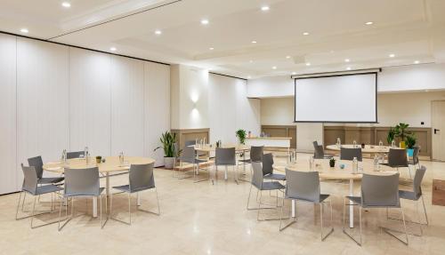 a conference room with tables and chairs and a projection screen at INNSiDE by Meliá Barcelona Apolo in Barcelona