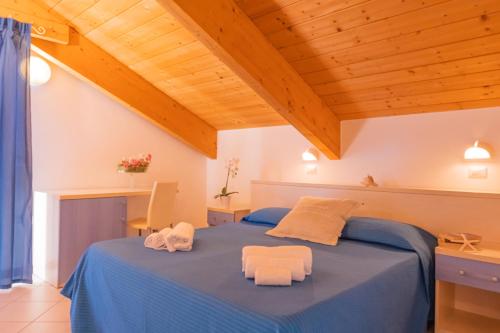 a bedroom with a blue bed with two towels at Hotel Merano in Misano Adriatico