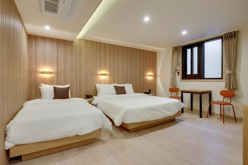 Habitación de hotel con 2 camas y mesa en Two H Hotel, en Busan