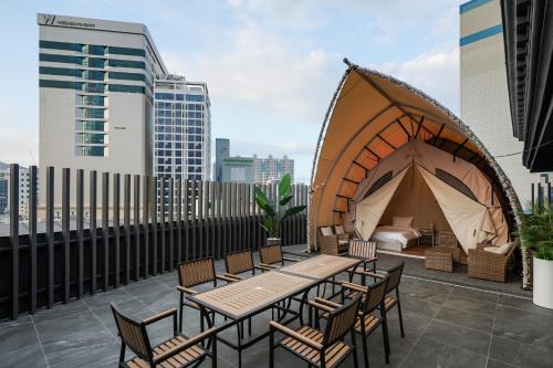a tent on a rooftop with a bed and chairs at Two H Hotel in Busan