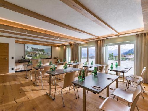 a restaurant with tables and chairs and windows at Hotel Waldfriede - Der Logenplatz im Zillertal in Fügen