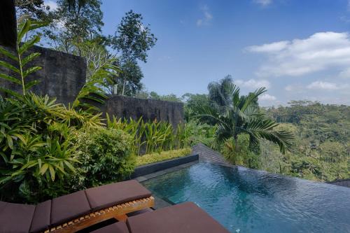 a swimming pool with a view of the jungle at Black Penny Villas Ubud in Ubud