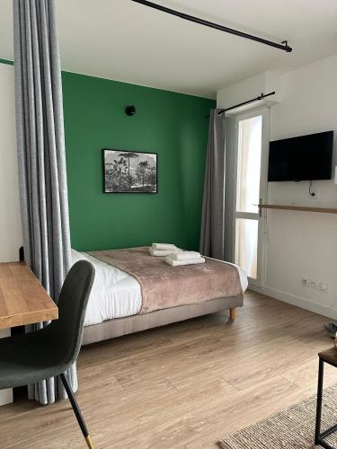 - une chambre dotée d'un mur vert avec un lit et une chaise dans l'établissement L’Atelier Sauvage - Studio Paisible Triangle d'Or, à Bordeaux