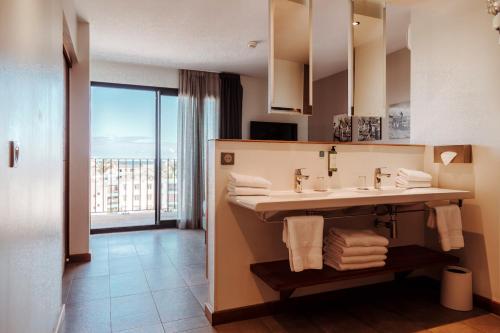 a bathroom with a sink and a large window at Hotel Le Saint Pierre ÎLe De La Reunion. in Saint-Pierre