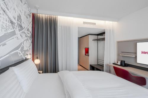 a bedroom with a white bed and a flat screen tv at IntercityHotel Paderborn in Paderborn