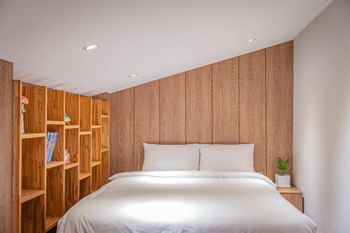 Schlafzimmer mit einem weißen Bett und Holzwänden in der Unterkunft The Private Hamdeok in Jeju-do