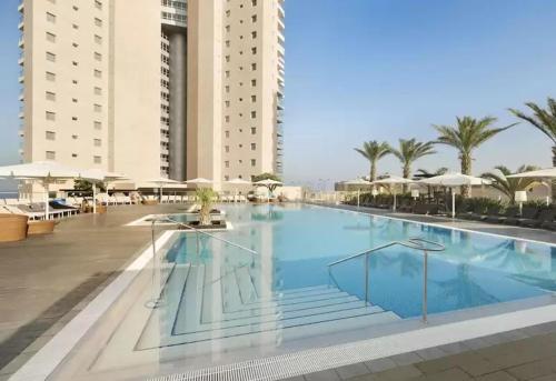 a large swimming pool in a resort with buildings at מול החוף במלון רמדה נתניה in Netanya