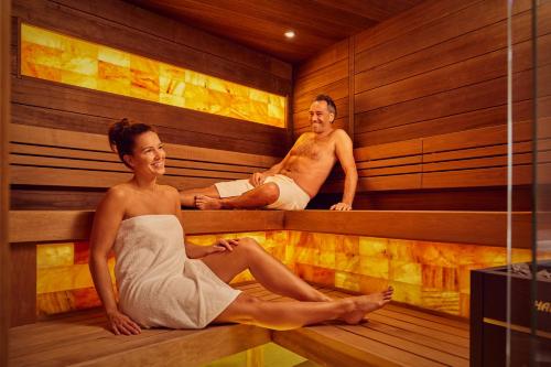 a man and woman sitting in a sauna at Badhotel Renesse in Renesse