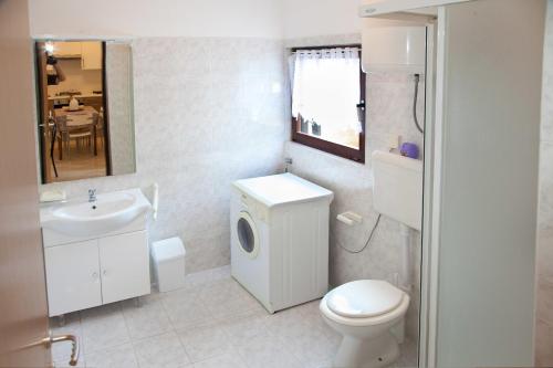a bathroom with a white toilet and a sink at Kucica Lusi in Ližnjan