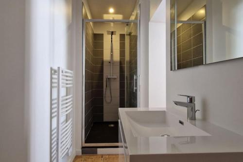 een witte badkamer met een wastafel en een douche bij La Parqueterie - 2 pas des thermes - 6 voyageurs in Bagnères-de-Bigorre