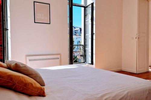 1 dormitorio con cama blanca y ventana grande en La Parqueterie - 2 pas des thermes - 6 voyageurs, en Bagnères-de-Bigorre
