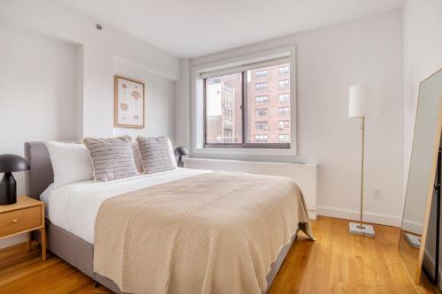 a white bedroom with a large bed and a window at Chelsea 1br w doorman gym nr Union Square NYC-1240 in New York