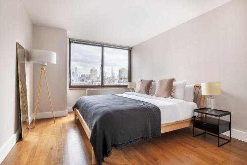 a white bedroom with a large bed and a window at UES 1BR w Gym WD nr Central Park NYC-1296 in New York