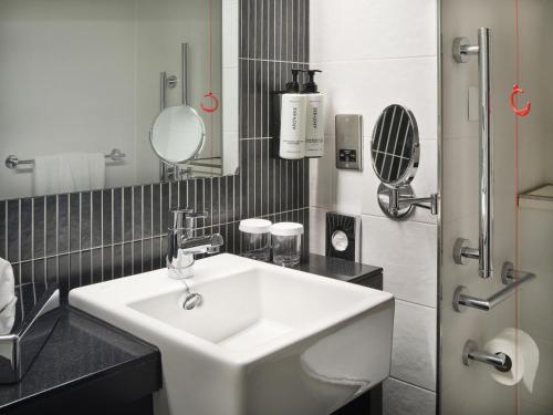 a bathroom with a sink and a toilet and a mirror at Crowne Plaza Birmingham City, an IHG Hotel in Birmingham