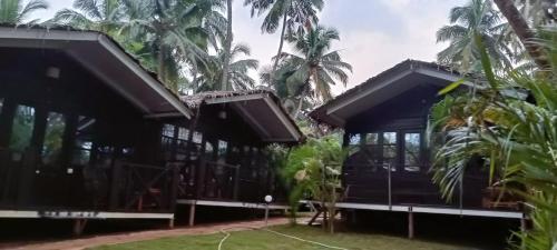a house with black roofs and palm trees at Seascape by Sand Sapphire in Canacona