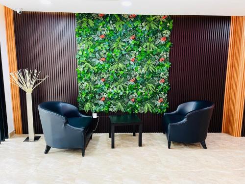 two chairs and a wall with a plant at Cozy Hotel@ KL Sentral in Kuala Lumpur
